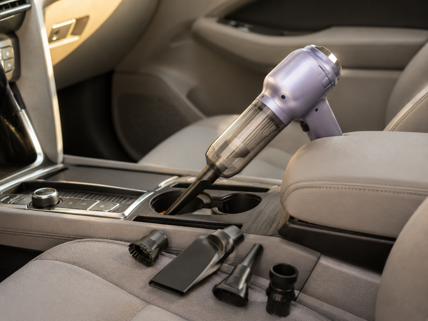 Compact cordless handheld vacuum cleaning crumbs and dust from the center console of a modern car.