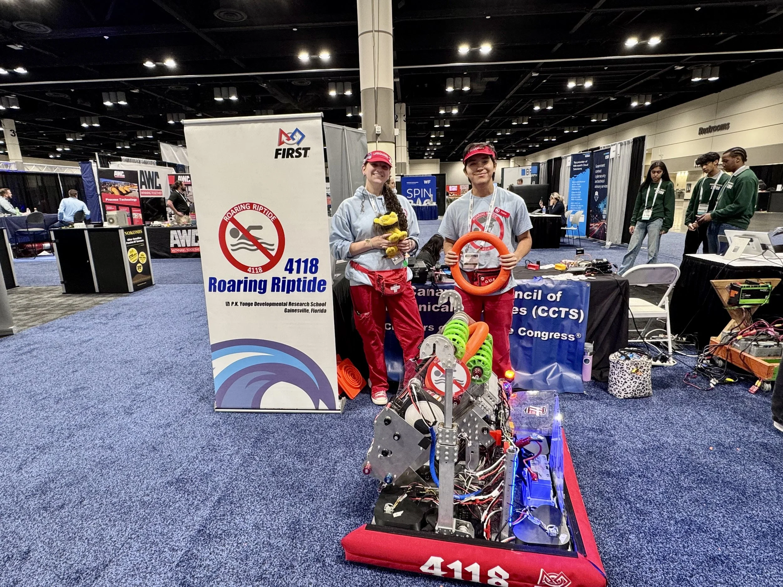 Two students showcase their 2024 season robot at the Spacecom conference.