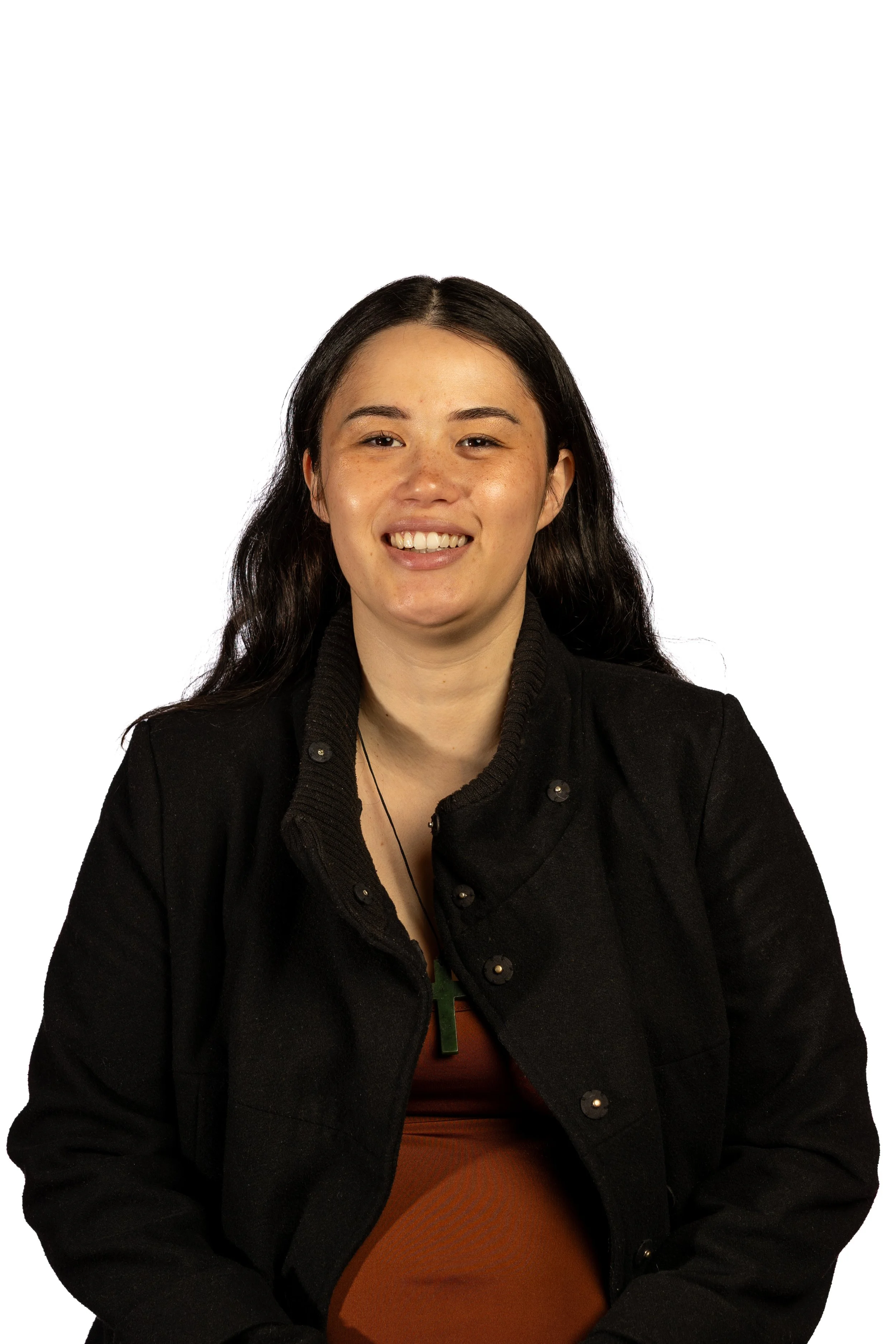 A young woman with long dark hair smiling at the camera, wearing a black jacket and brown top, against a plain white background.