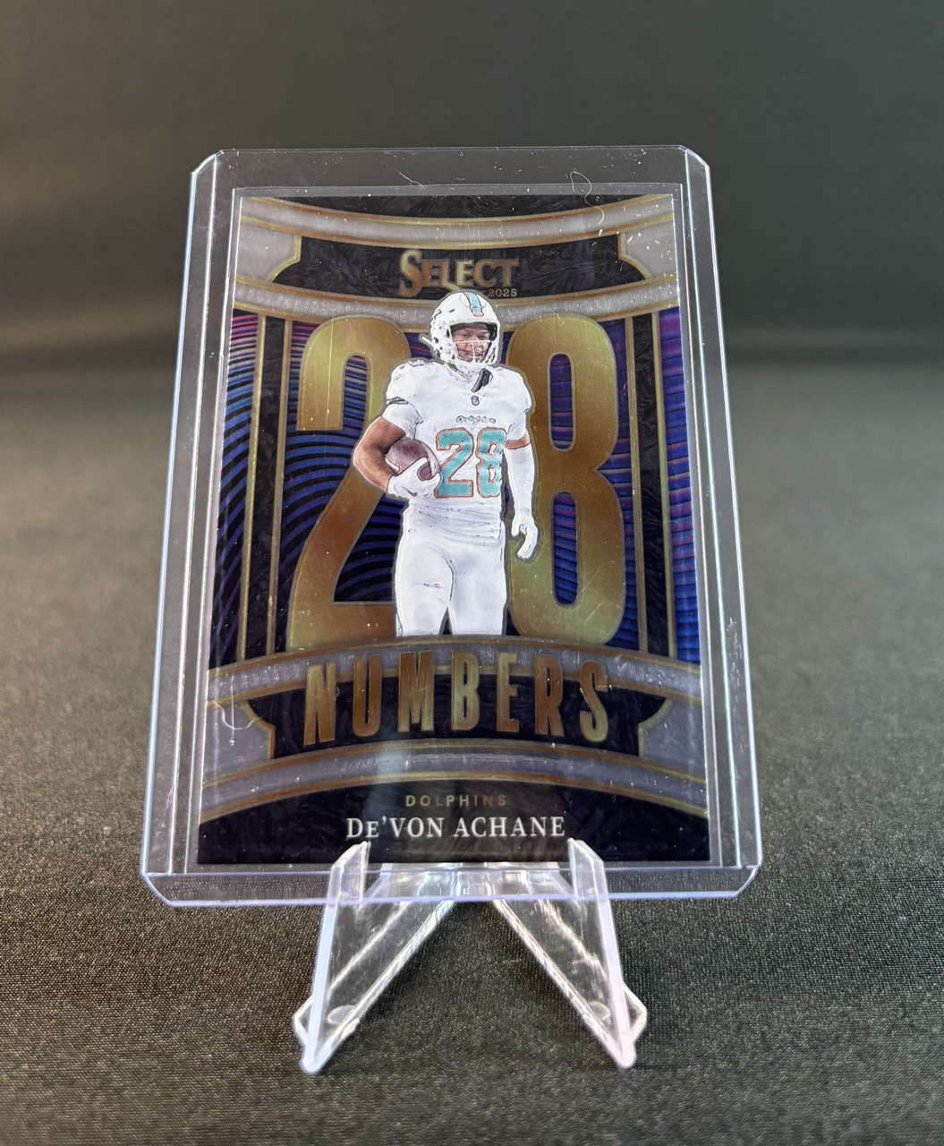 Sports trading card featuring De'Von Achane, a Miami Dolphins football player, holding a football. The card celebrates 200+ career rushing yards and shows vibrant colors with a large number 200 and the words 'Numb3rs' and 'Dolphins' at the bottom.