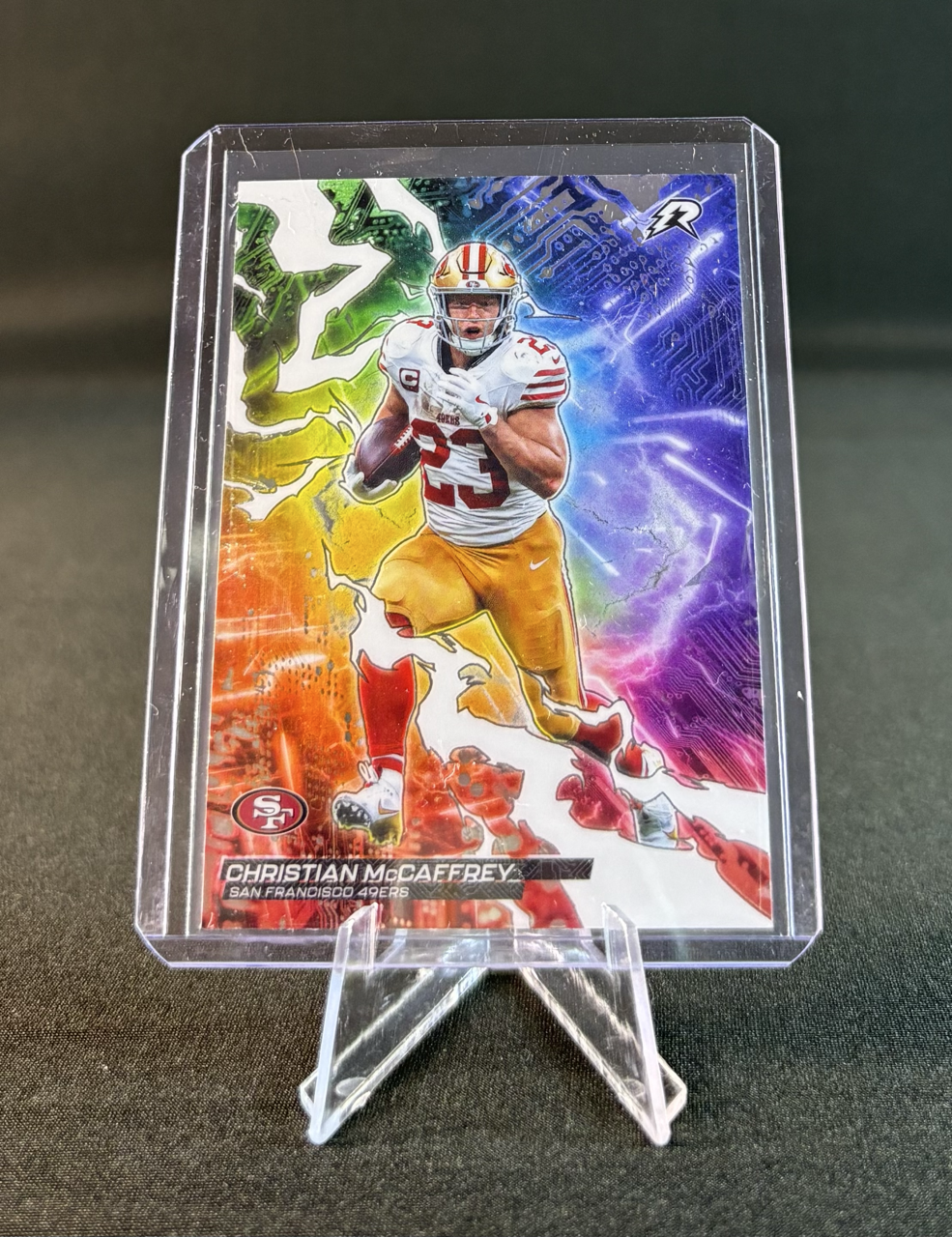 Colorful sports card featuring Christian McCaffrey of the San Francisco 49ers, with a digital lightning background in blue, purple, red, and green.