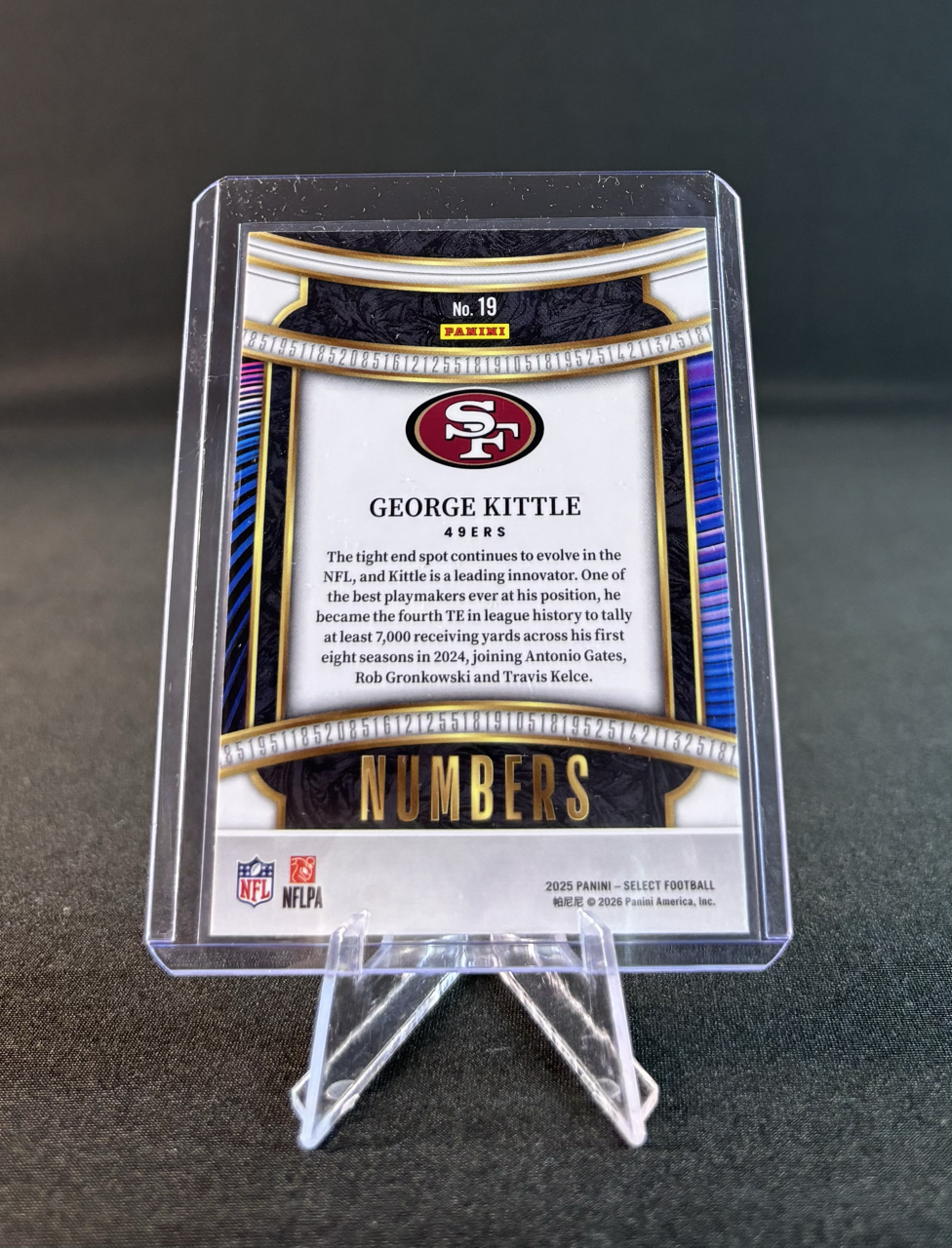 Football trading card of George Kittle, a tight end for the San Francisco 49ers, displayed on a clear stand.