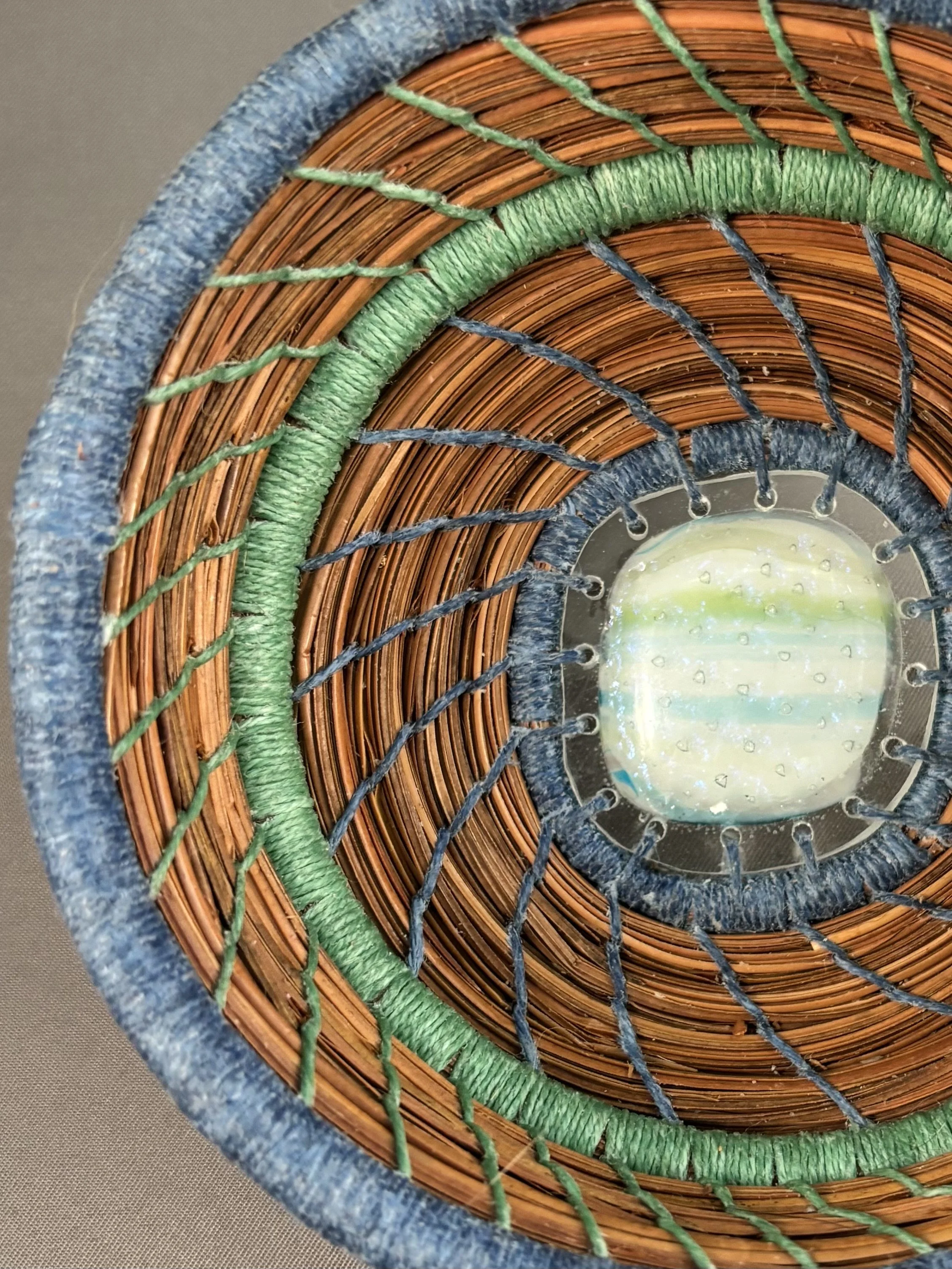 Detail of blue outer infinity row and green wrapped row of Quiet Waters pine needle basket.