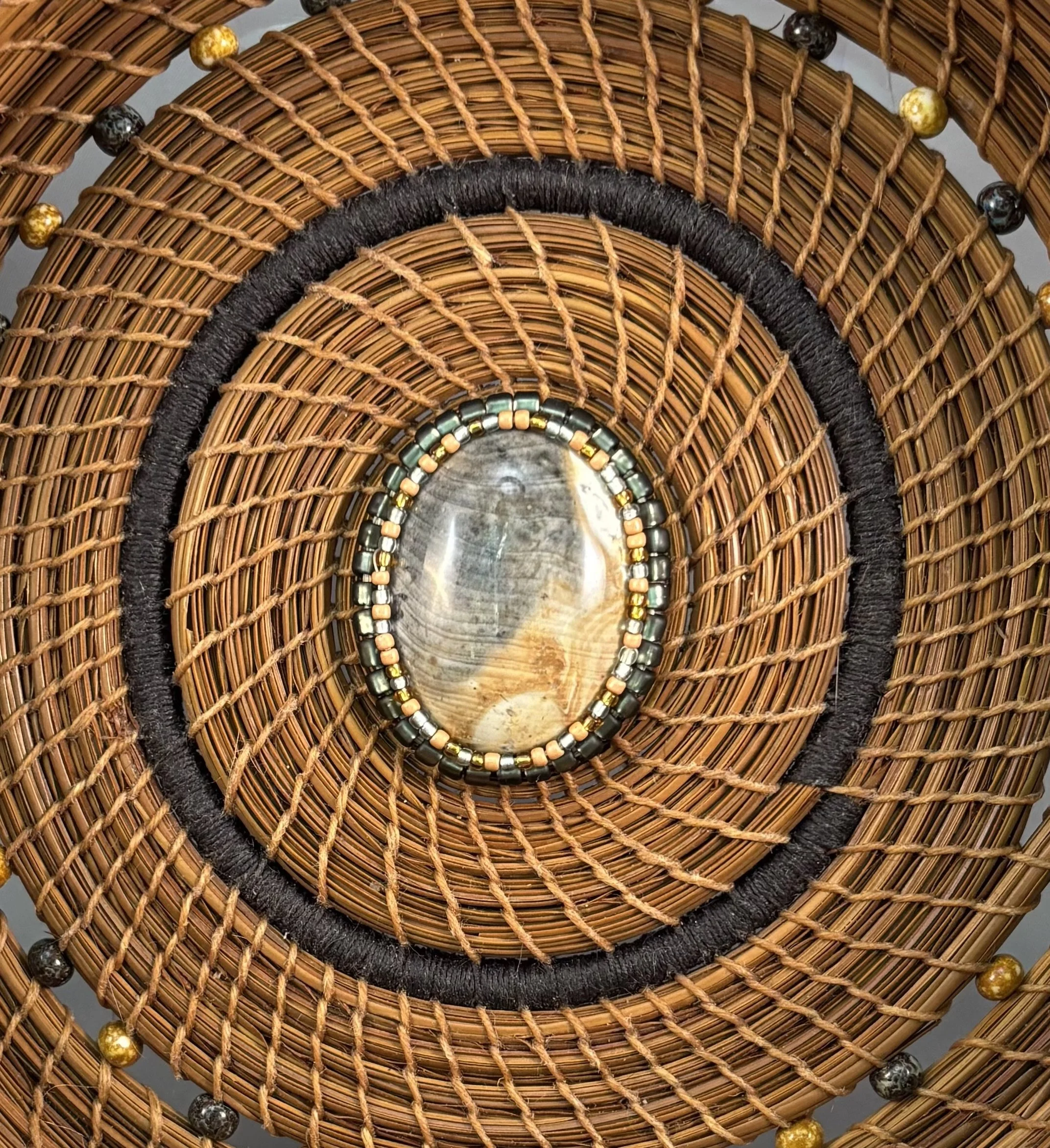 Detail of the center in Gathering Light showing the polished stone surround by silver-grey metallic glass beads and smaller seed beads.