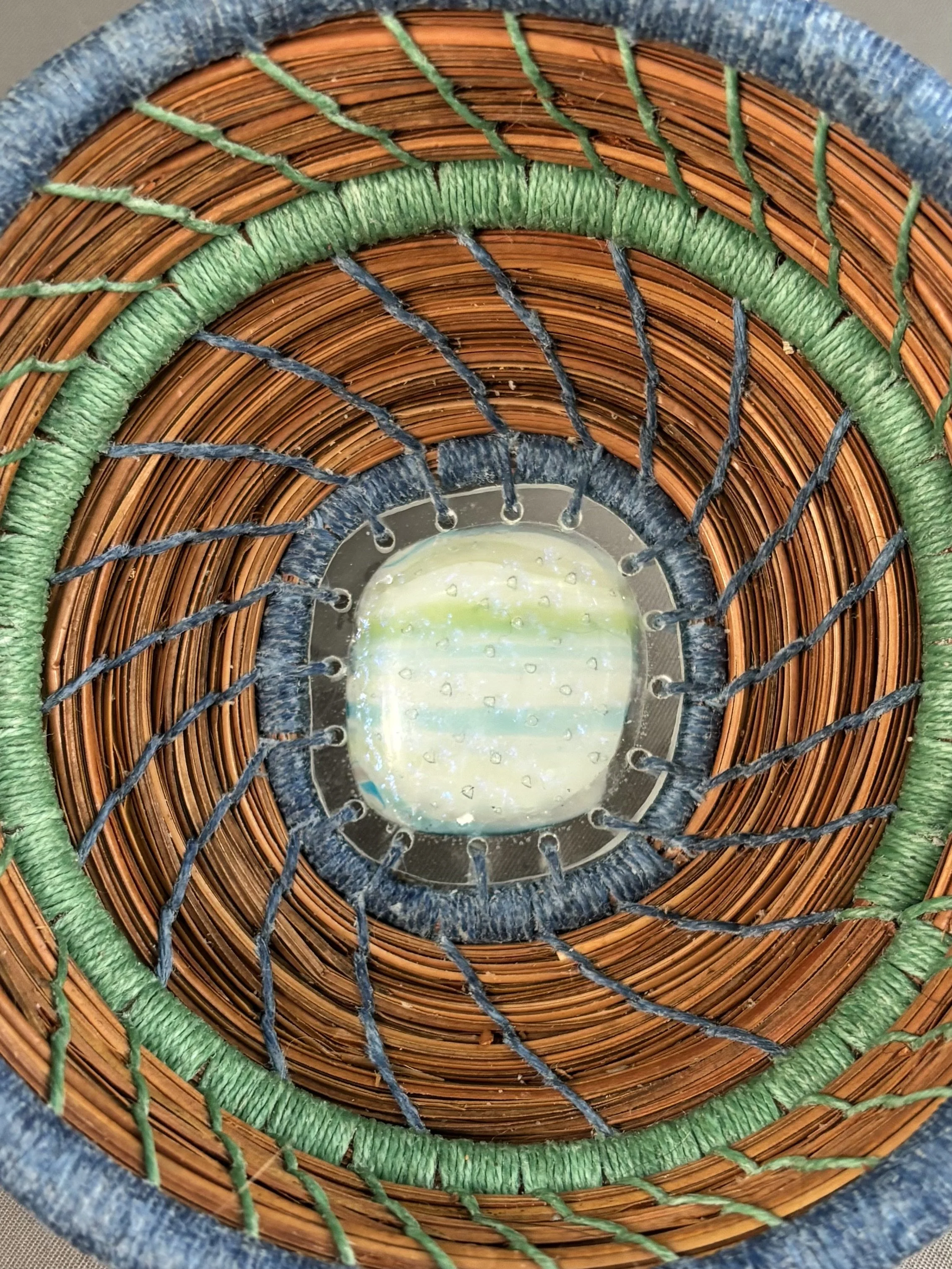 Close-up of blue and green glass center surrounded by Williamsburg blue and sage green coiled pine needles.