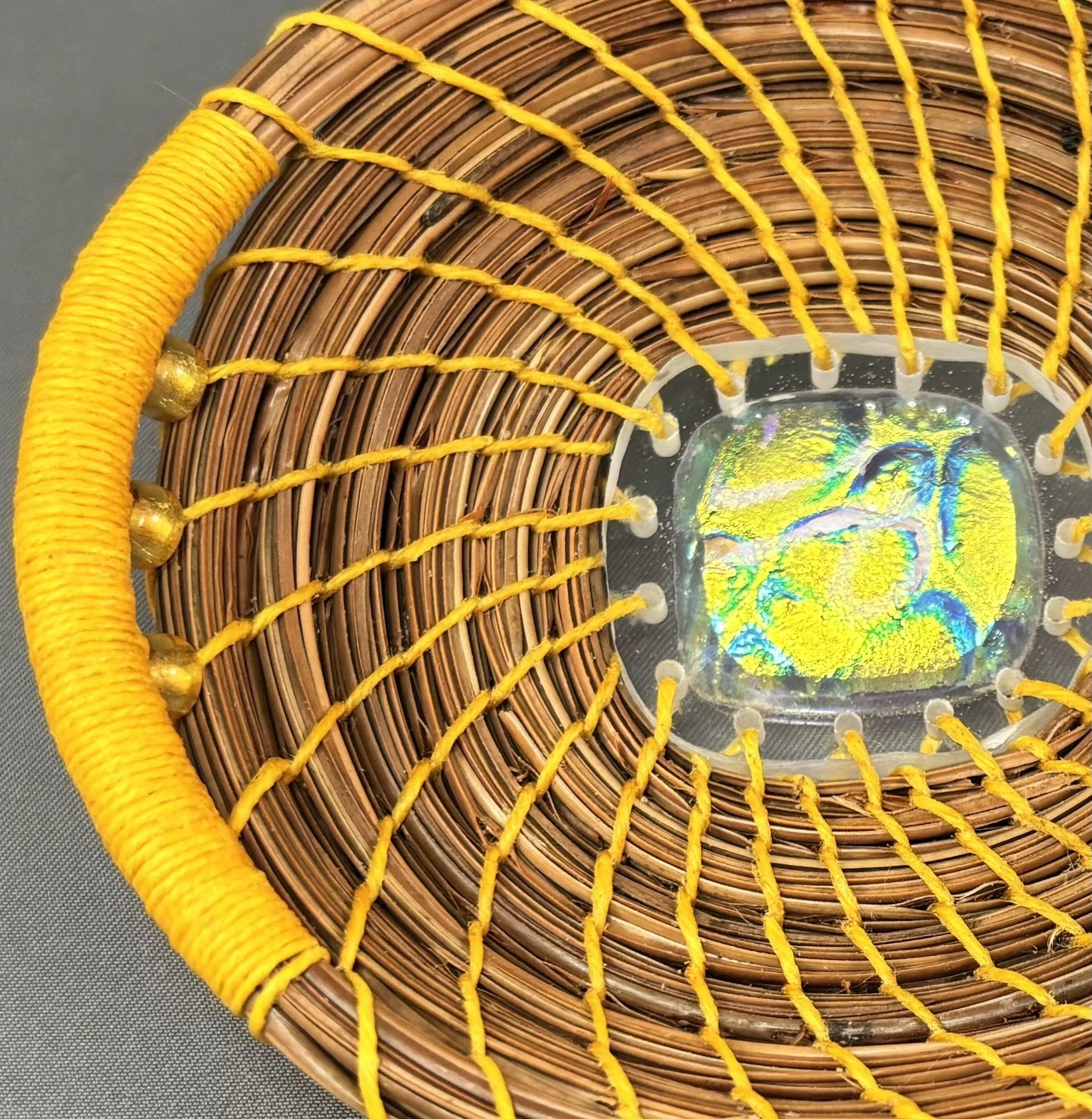 Detail of Held in Light showing yellow glass beads, bright autumn yellow thread, and coiled natural pine needles.