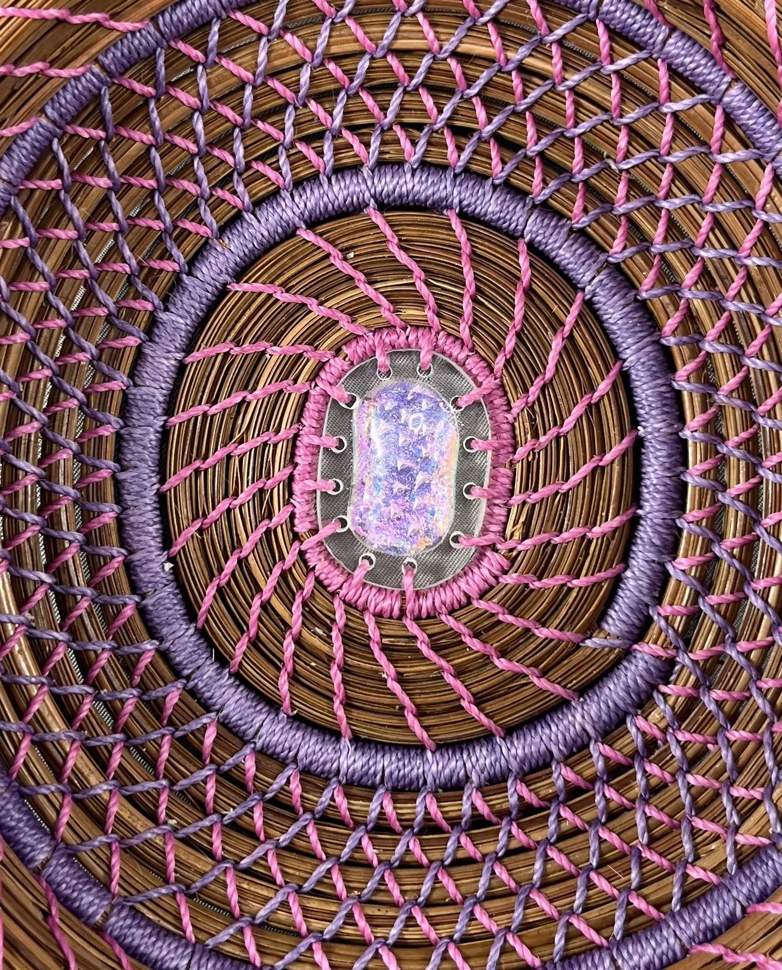 Close-up of Changing Light showing its pink and purple dichroic glass center and intricate stitching.
