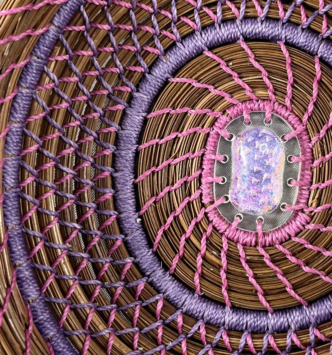 Changing Light, a contemporary pine needle basket with fuchsia and lavender diamond stitching and dichroic glass center.