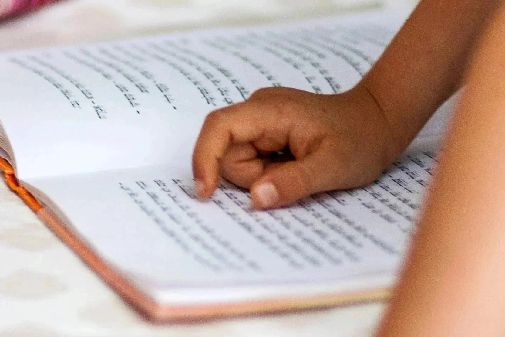 Close-up of a hand turning the pages of a notebook or journal with handwritten text.