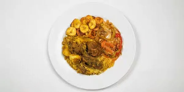 Plate of curry with vegetables, plantains, and rice.