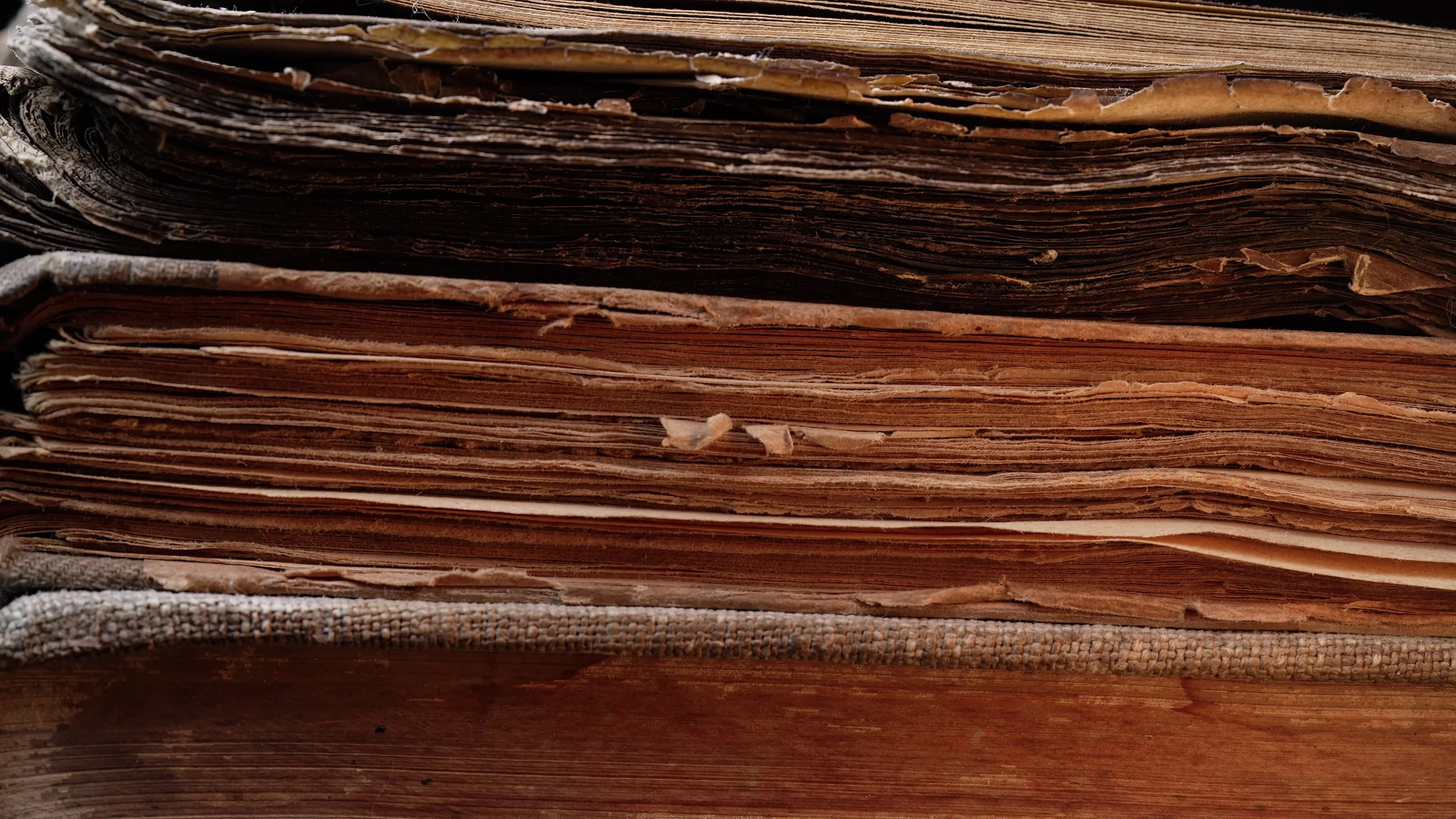 Close-up of old, weathered, and worn paper or parchment pages stacked together.