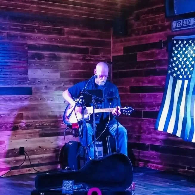 Larry Holly performing an intimate acoustic set at a rustic venue