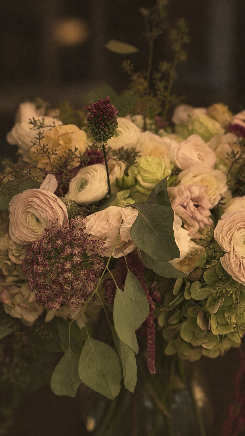 Close-up of a bouquet of flowers with cream and white roses, purple and pink accents, and green foliage.