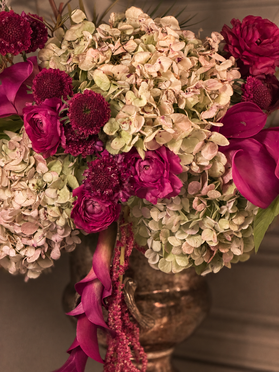 A bouquet of pink and white flowers, including hydrangeas, roses, calla lilies, and other blossoms in a decorative vase.