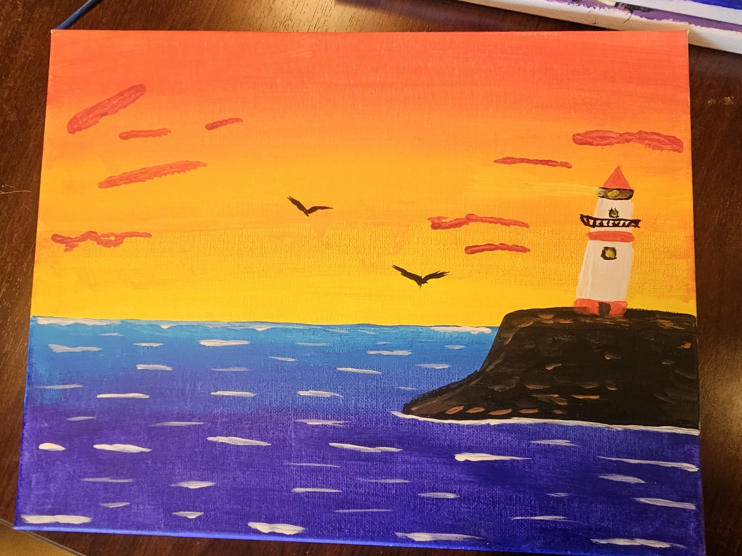 Painting of a sunset scene with a lighthouse on a rock, flying seagulls, and a colorful sky with clouds, water, and waves.