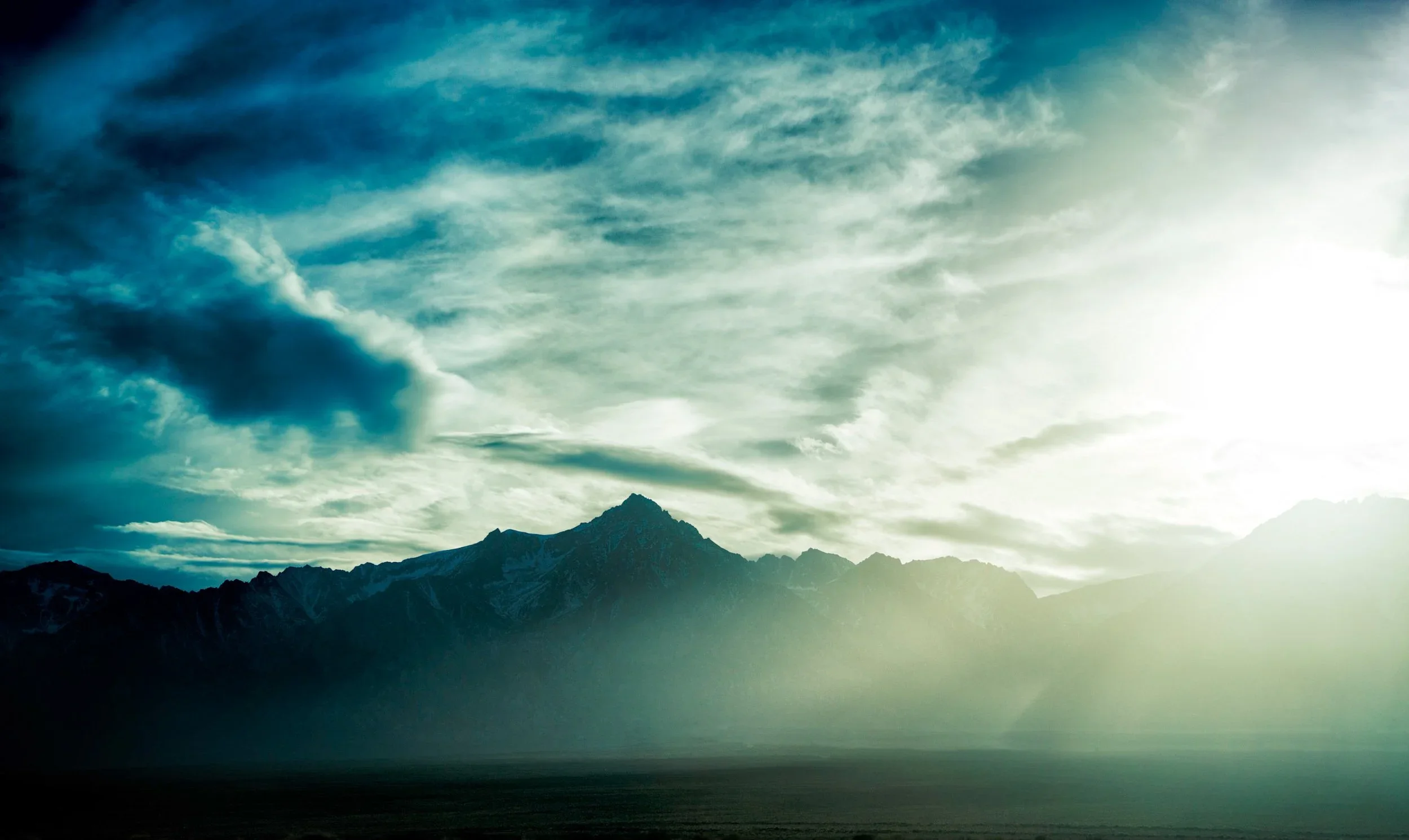 Scenic view of mountain range with a cloudy sky and sunlight shining through clouds.