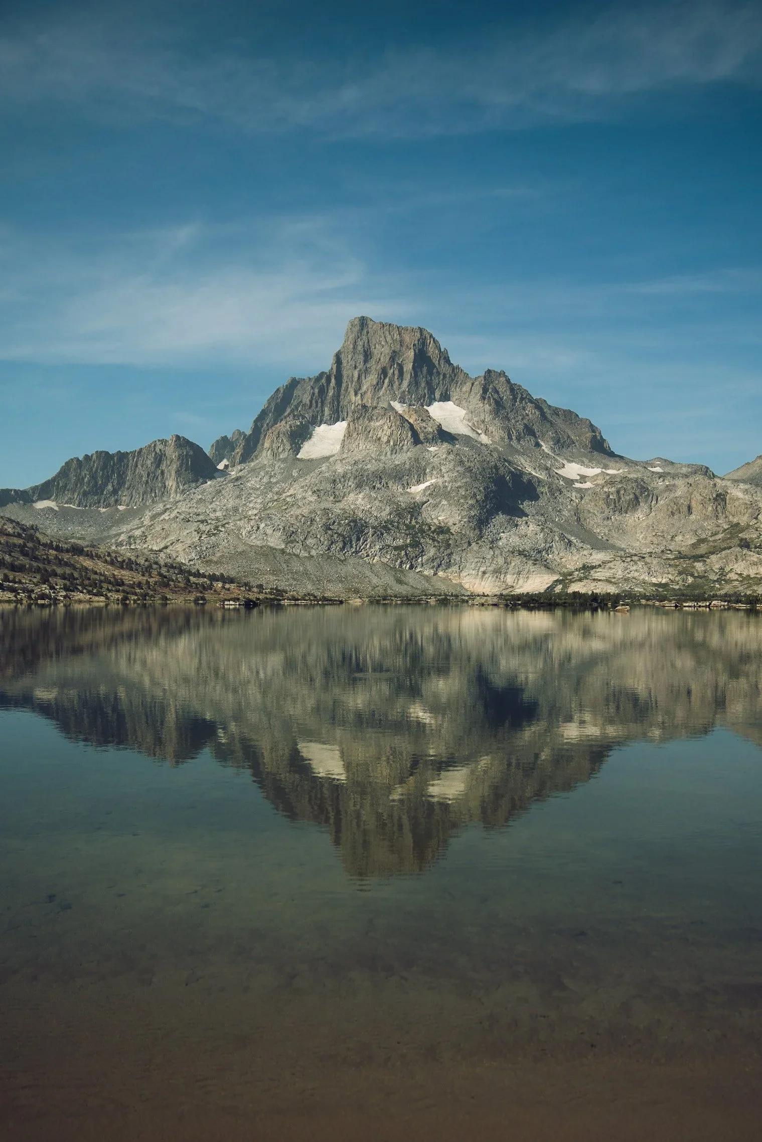 A mountain reflected in a calm lake with a clear blue sky.