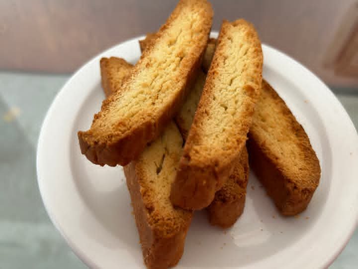 Four paximadia, Greek cookies similar to biscotti, stacked on a white plate.