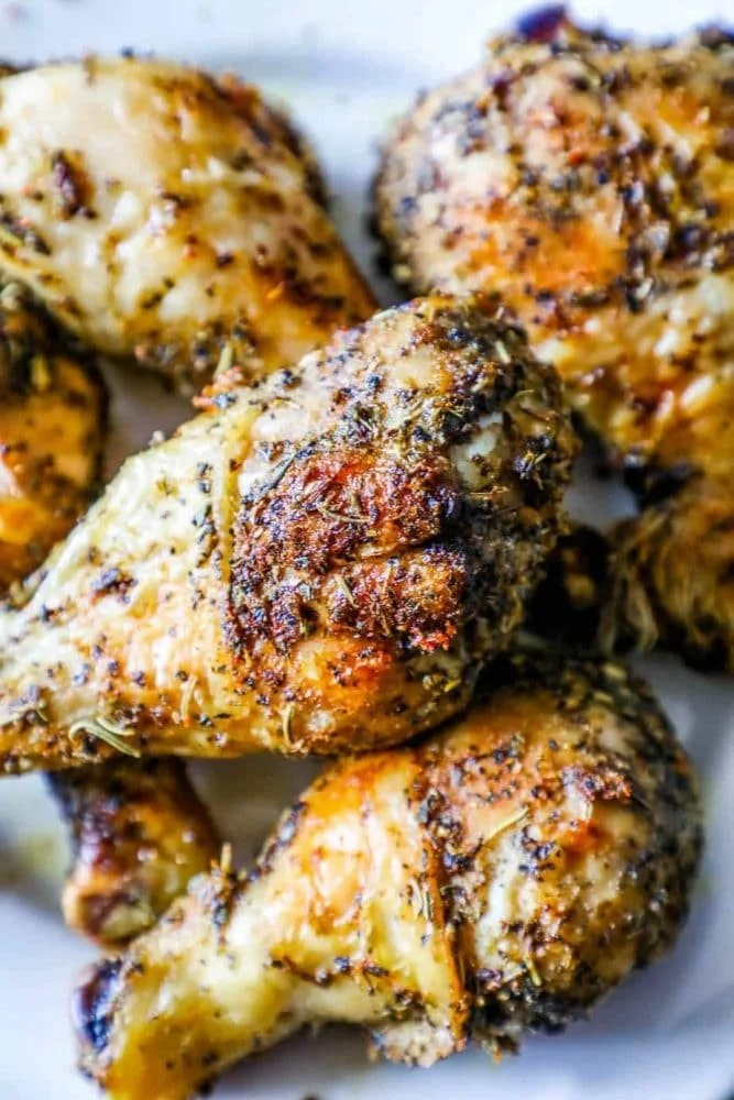 Close-up of roasted chicken drumsticks with Greek herbs and spices.