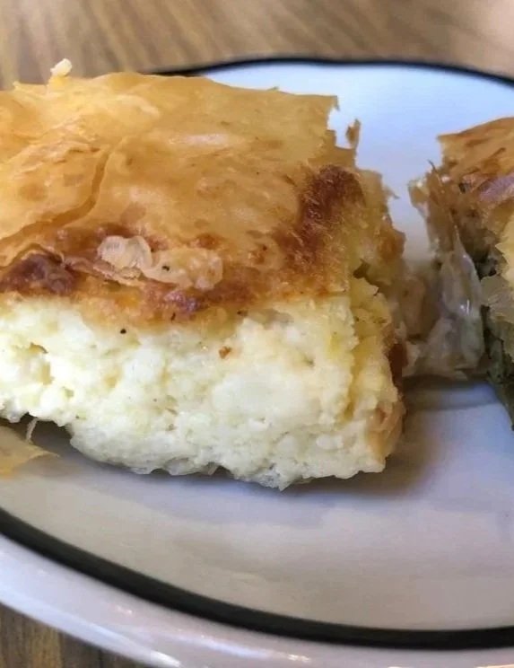 A close-up of a portion of Greek tiropita with a golden-brown crispy phyllo top