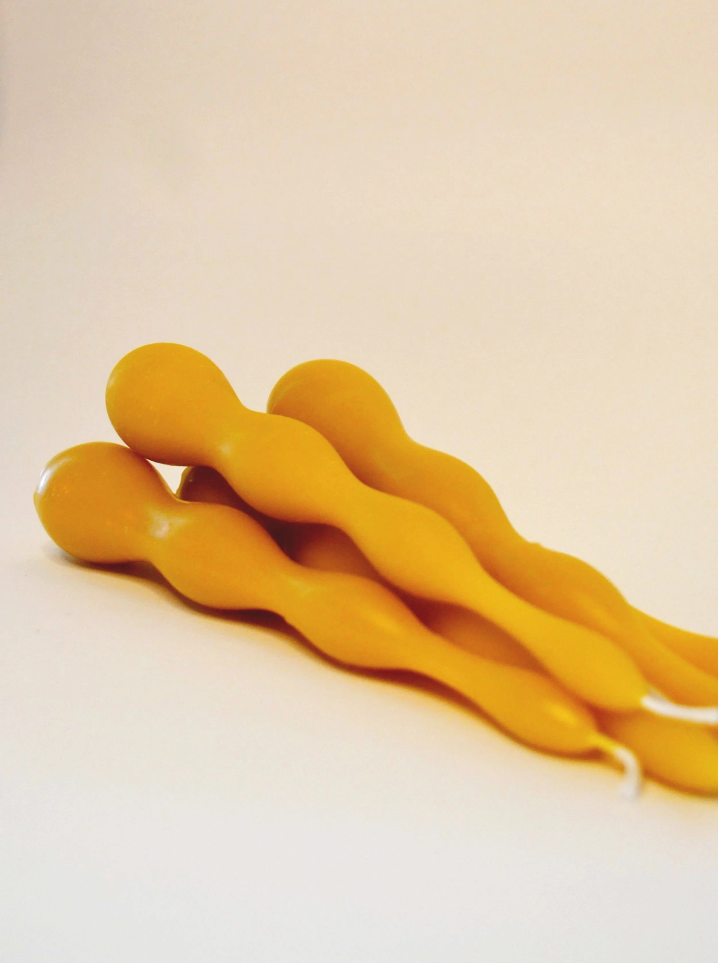 Pure beeswax handmade wavy taper candles, bundled together in a neutral setting. Clean burning, unscented artisan tapered candle.