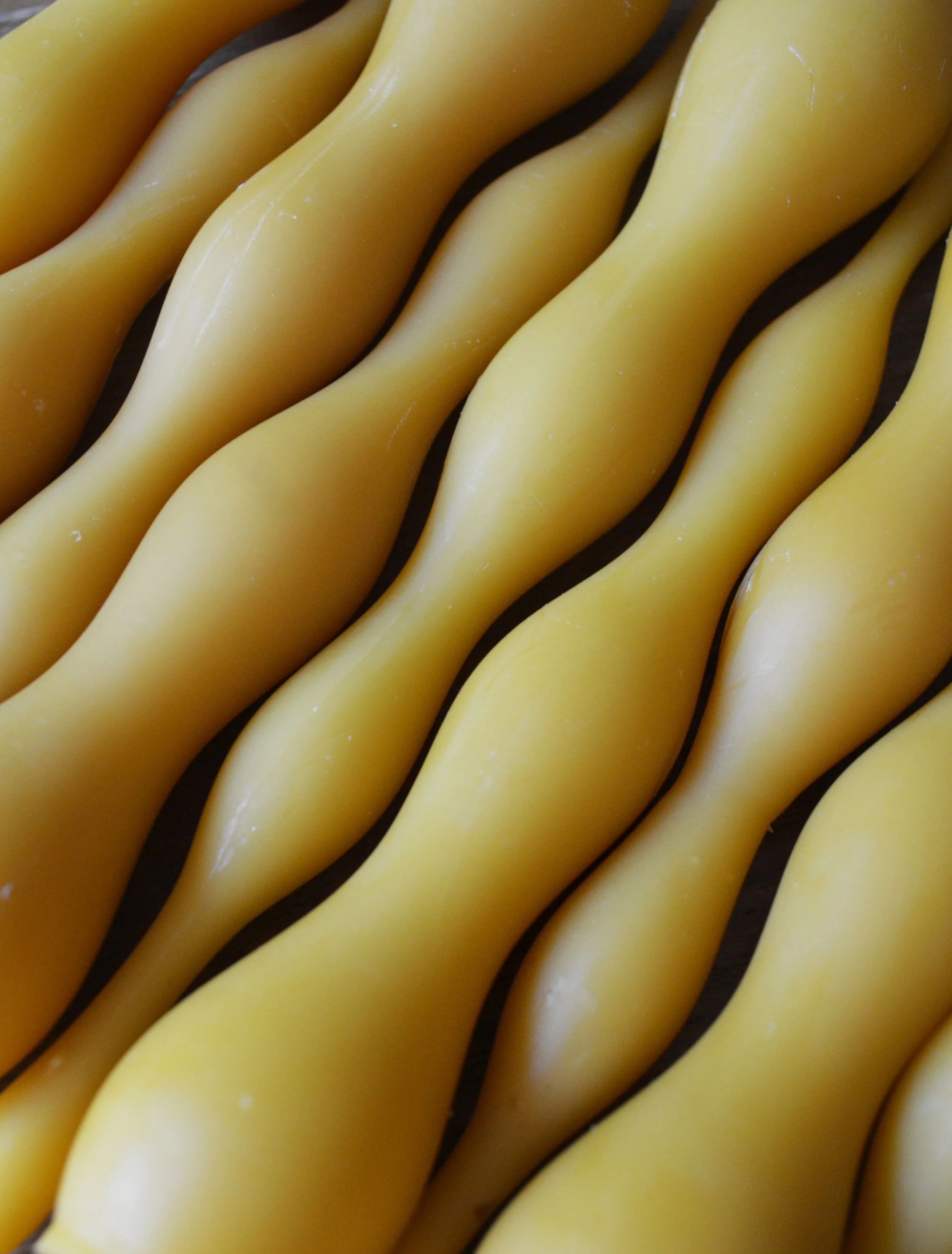 Detailed view of pure beeswax handmade wavy taper candles to show texture.