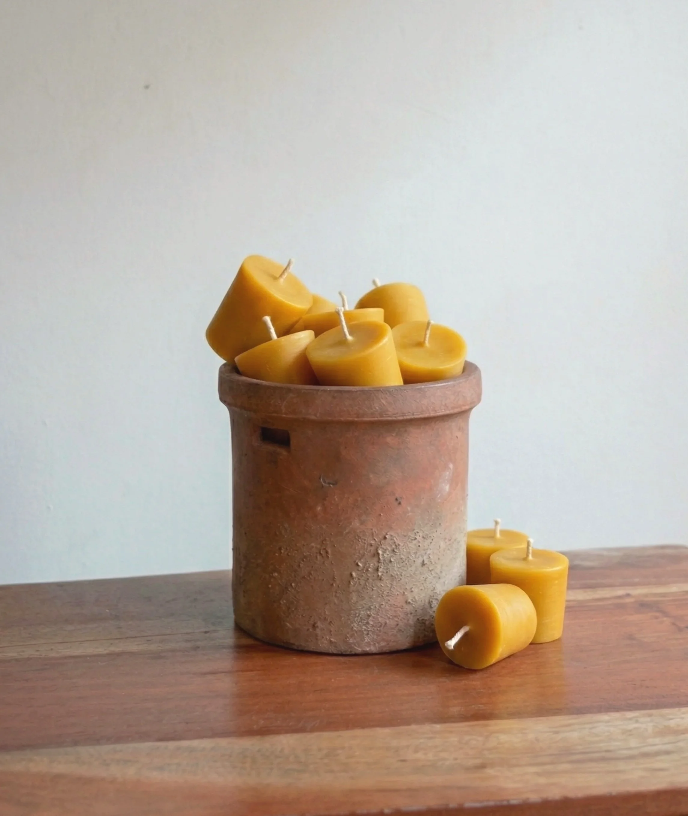 A clay pot filled with handmade pure beeswax votive candles. Natural clean burning candlelight.
