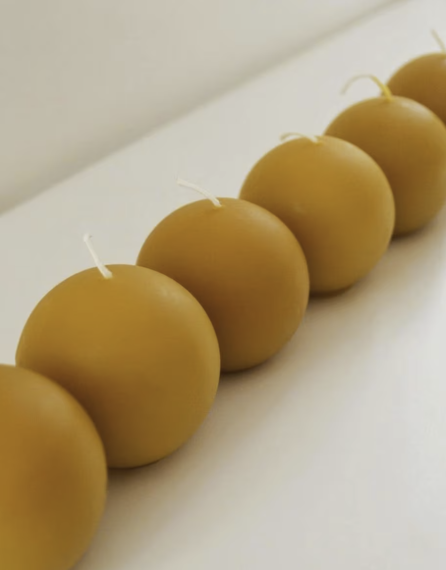 Natural beeswax orb candles on a work table. Unscented candlelight for evening rituals and natural ambiance.
