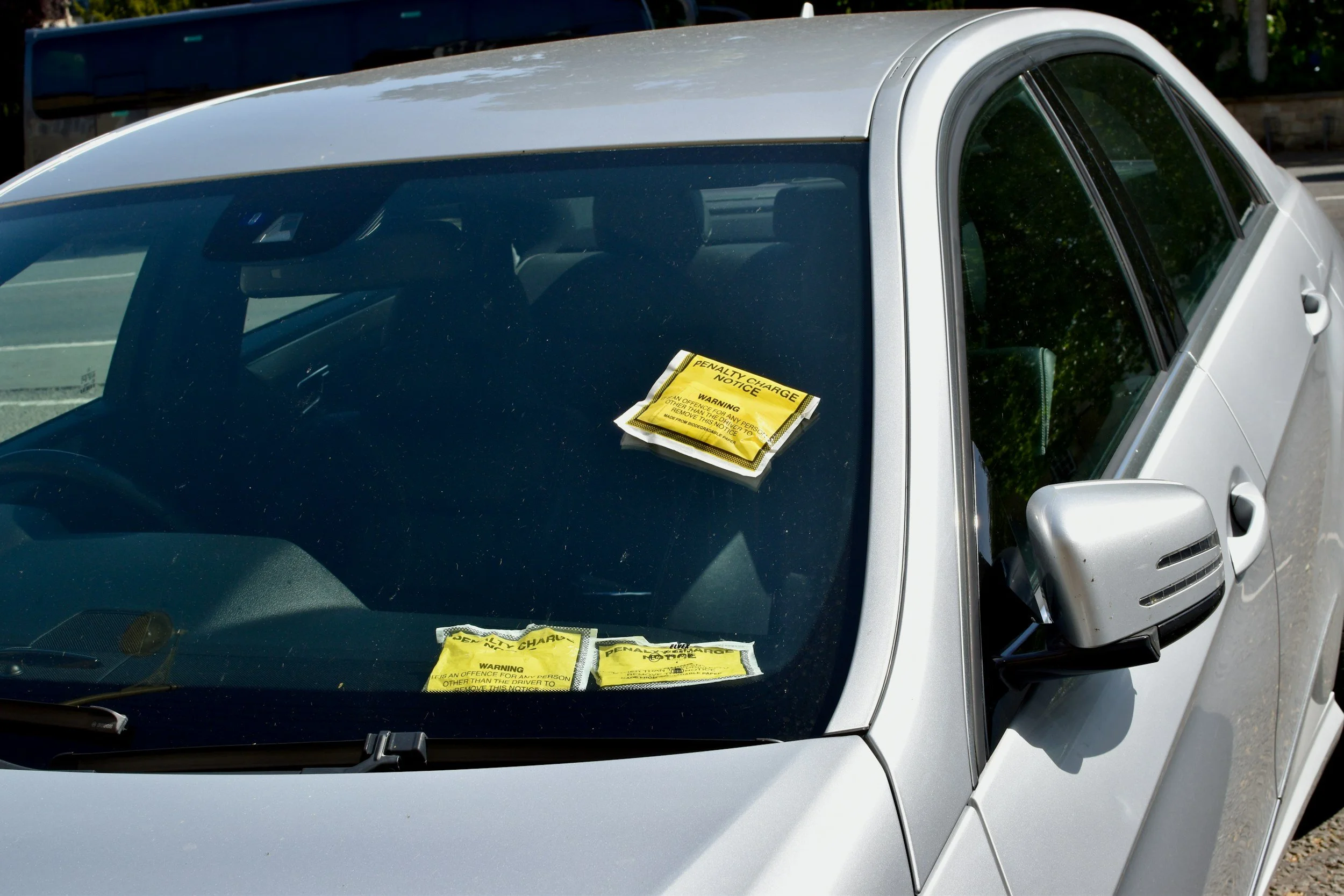 Silver car with a yellow warning ticket on the windshield.