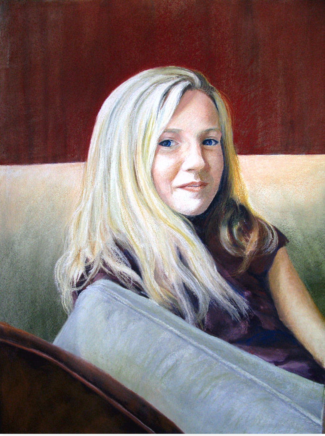 A portrait of a woman with long blonde hair, sitting on a couch with a red and beige background.