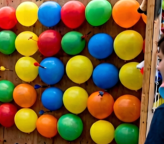 Colorful plastic balls arranged on a wooden stand at a carnival game.