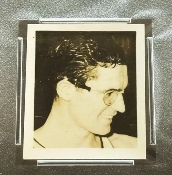 Black and white portrait of a man with glasses, curly hair, smiling slightly, shown in profile.