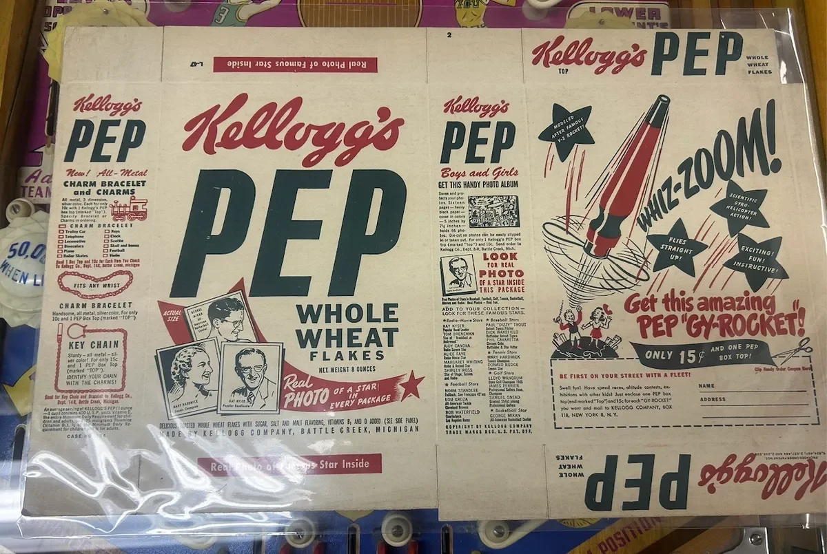 Vintage Kellogg's PEP cereal box featuring whole wheat flakes, a rocket illustration with the text "WHIZ-ZOOM!" and promotional content for a photo album and charm bracelet kit.