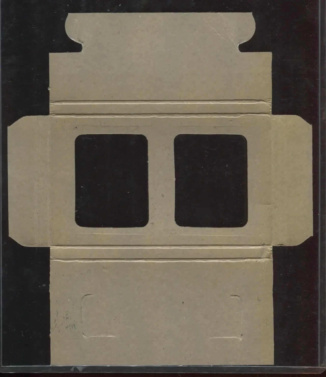 A cardboard insert with cutouts resembling a car's front view, placed inside a black-bordered display box.