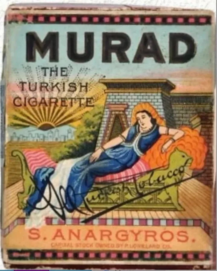A vintage cigarette pack labeled "Murad, The Turkish Cigarette" featuring an illustration of a woman relaxing on a chaise lounge with orange hair, wearing a blue dress, set against a background of a city and a sunset. The pack is signed with a signature in black ink at the bottom.