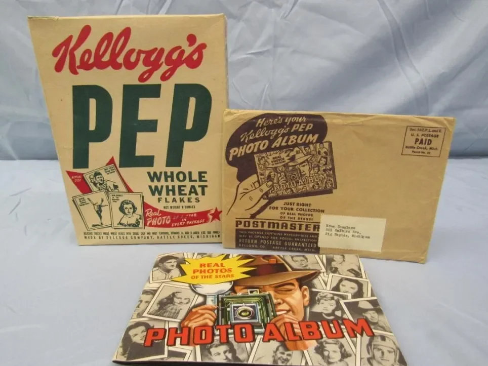 A vintage Kellogg's PEP Whole Wheat Flakes cereal box, a Kellogg's Ped photo album, and a photo album titled "Photo Album" with a collage of black-and-white photographs of people, featuring a man with a camera on the cover.