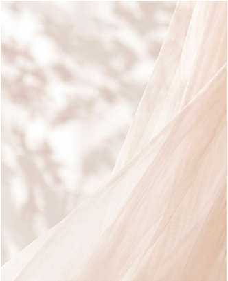 Close-up of a light-colored, flowing fabric, possibly a wedding dress, with a blurred, light background.