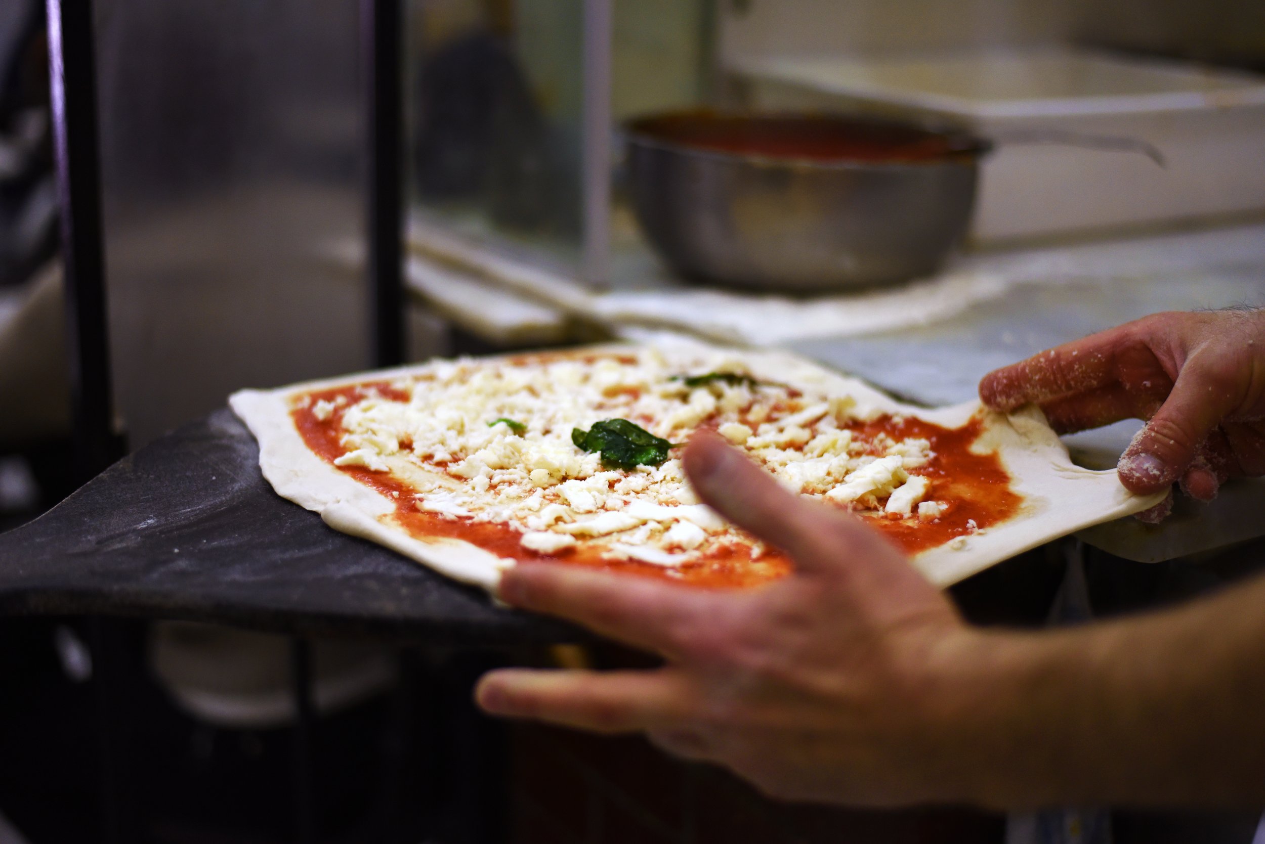 Traditional Neapolitan pizza being prepared with tomato, Agerola Fiordilatte and basil.
