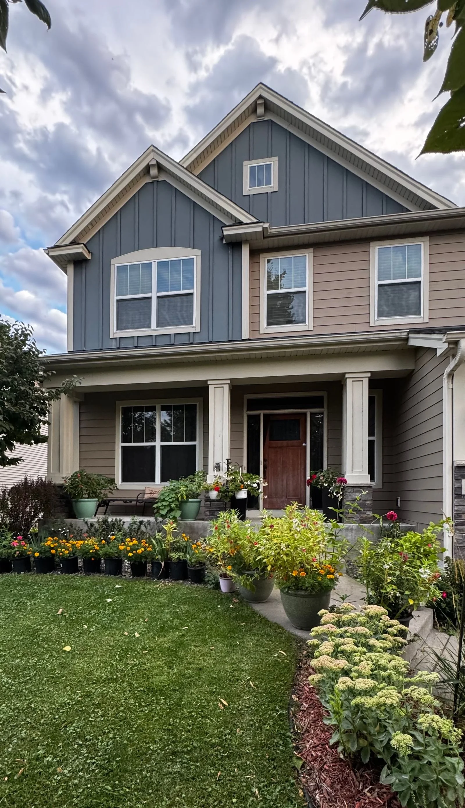 Two-story house with a landscaped front garden and flowering plants by the porch