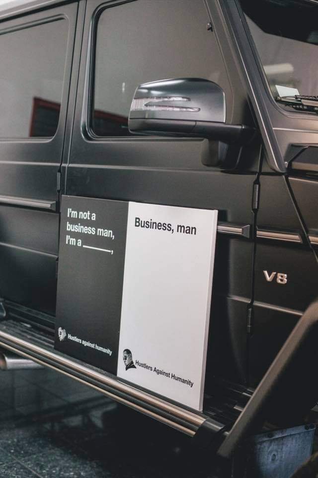 Black pickup truck with sign on door that reads "I'm not a business man, I'm a ______" and "Business, man." The sign has logos for Huskers Against Humanity and a person with a speech bubble.