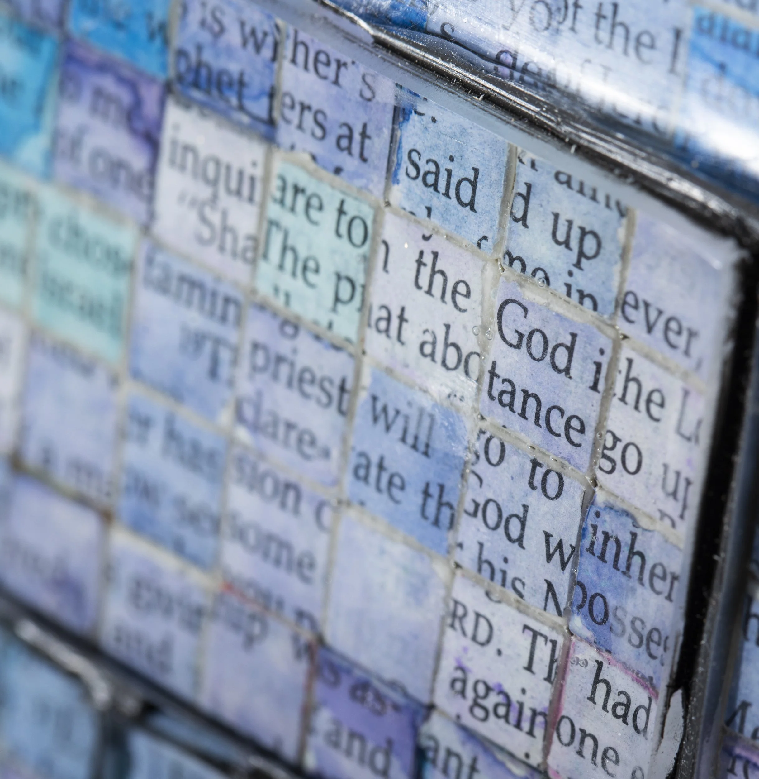 Detail of "A Study on Revolutions and Their Undoing", showing overlapping fragments of printed Bible text embedded beneath a glossy resin surface.