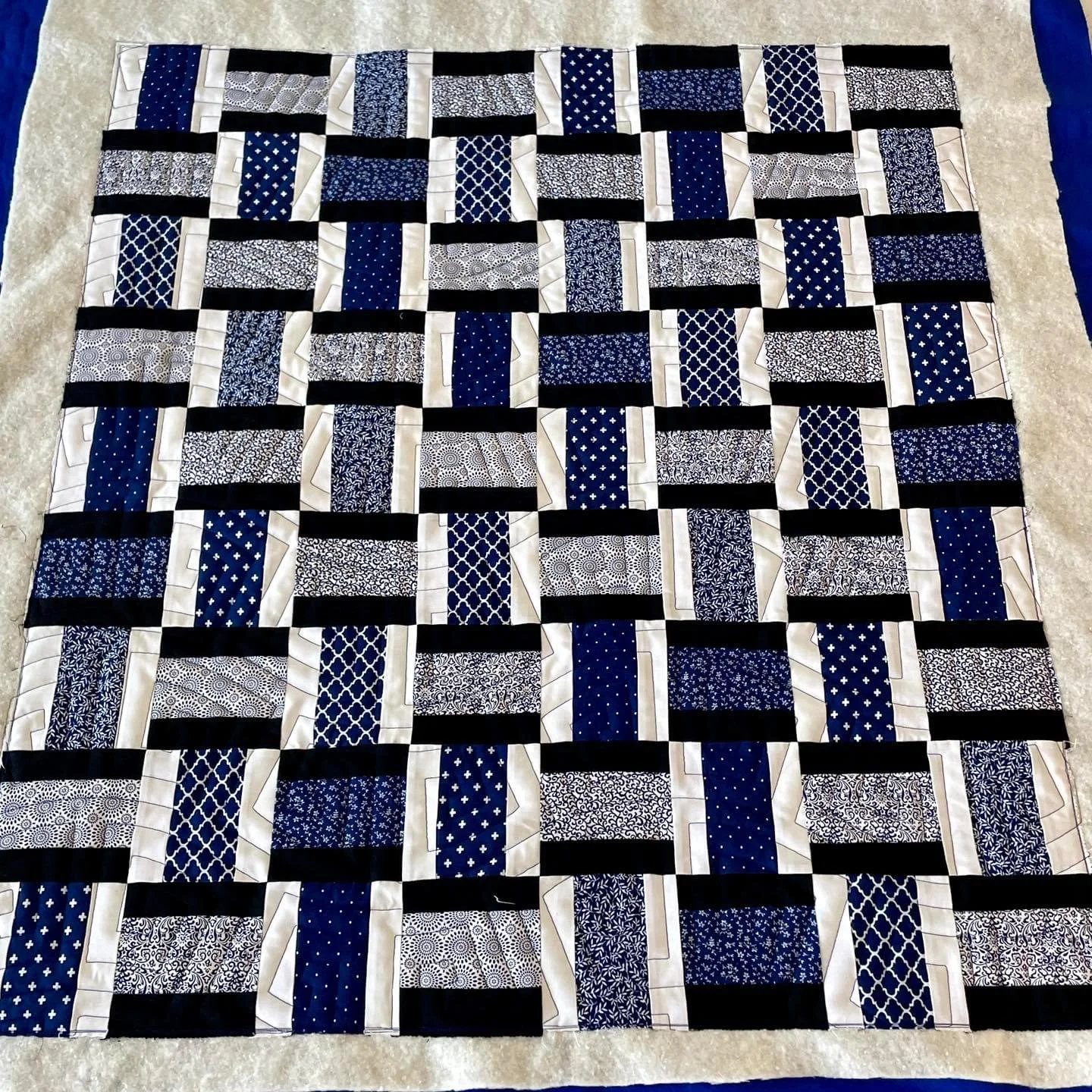 A quilt with black, white, and blue patterned fabric squares arranged in a checkerboard pattern.