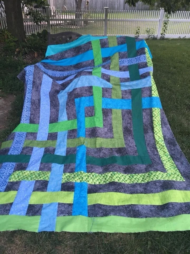 Colorful quilt with green, blue, and gray strips.