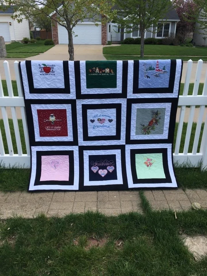A quilt with nine square patches, each with different embroidery designs.