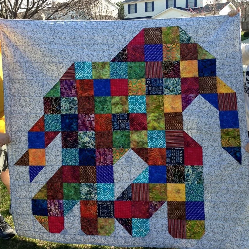Colorful stitched quilt with a elephant design, featuring various fabric squares and triangles.