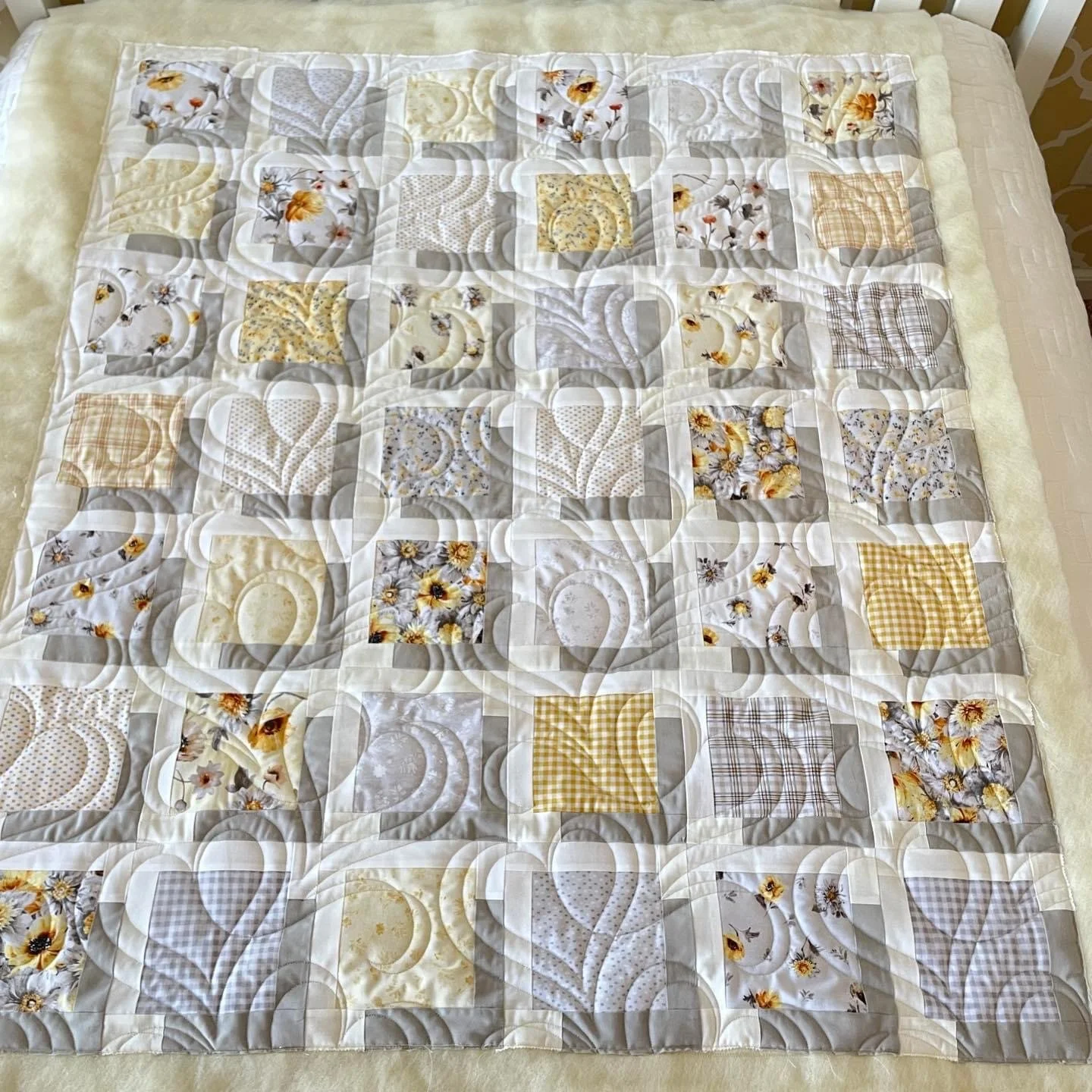 A quilt with a patchwork design of various floral and checkered fabric squares.