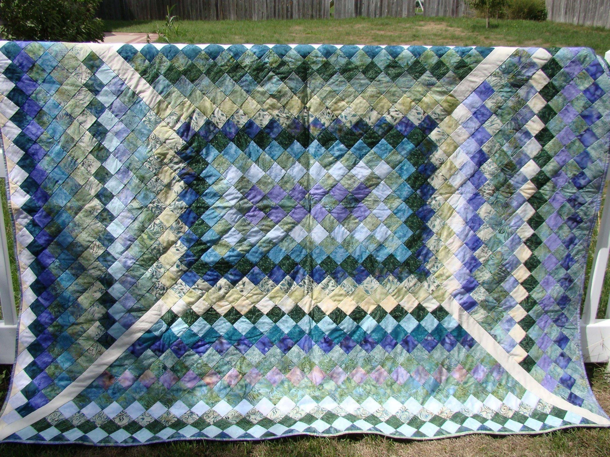 Colorful quilt with diamond patterns in blues, greens, and purples.
