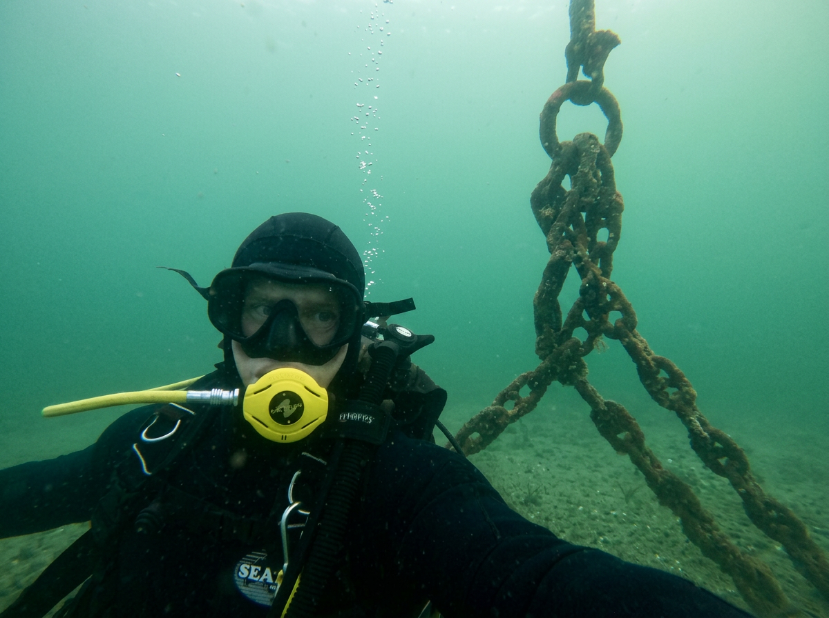 Scuba diver underwater near a rusty chain and anchor chain