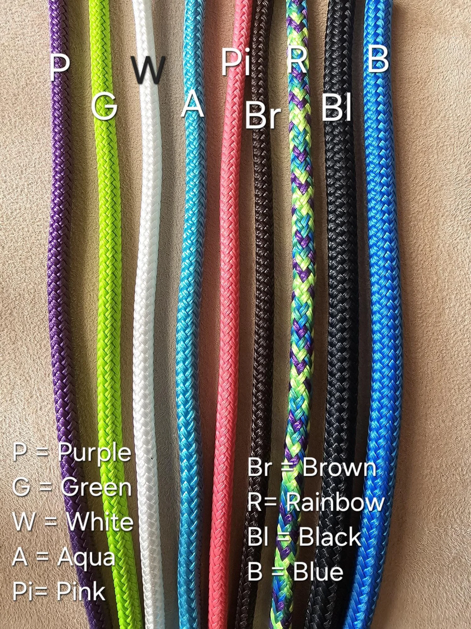 Arranged colorful braided ropes with labels indicating their colors: purple, green, white, pink, brown, multicolor rainbow, black, blue.