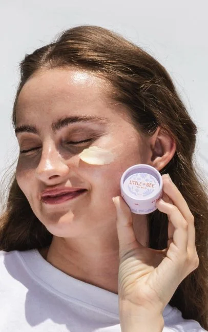 Little Bee brand photoshoot of woman applying mini balm product to face